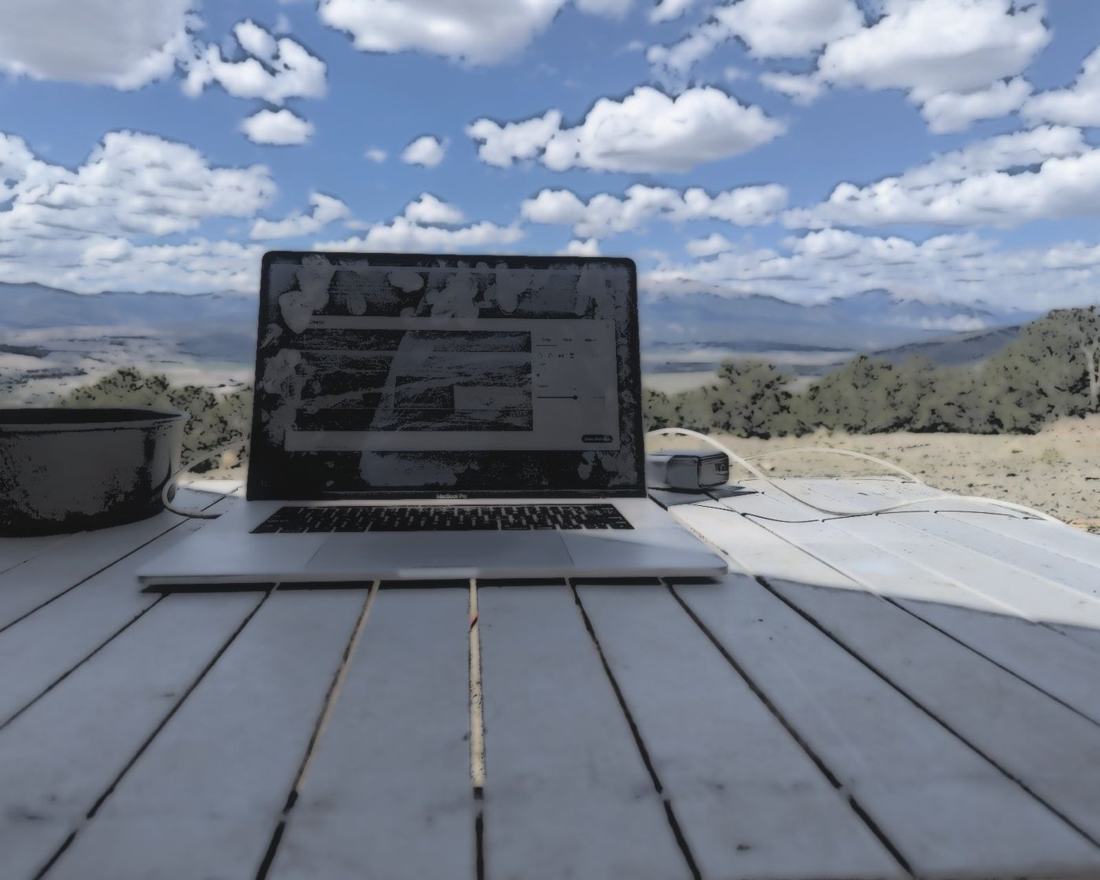 Jeremy's laptop open on an outdoor deck table under a big sky