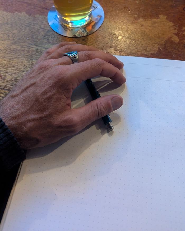 Jeremy's hand sketching in a dotted notebook